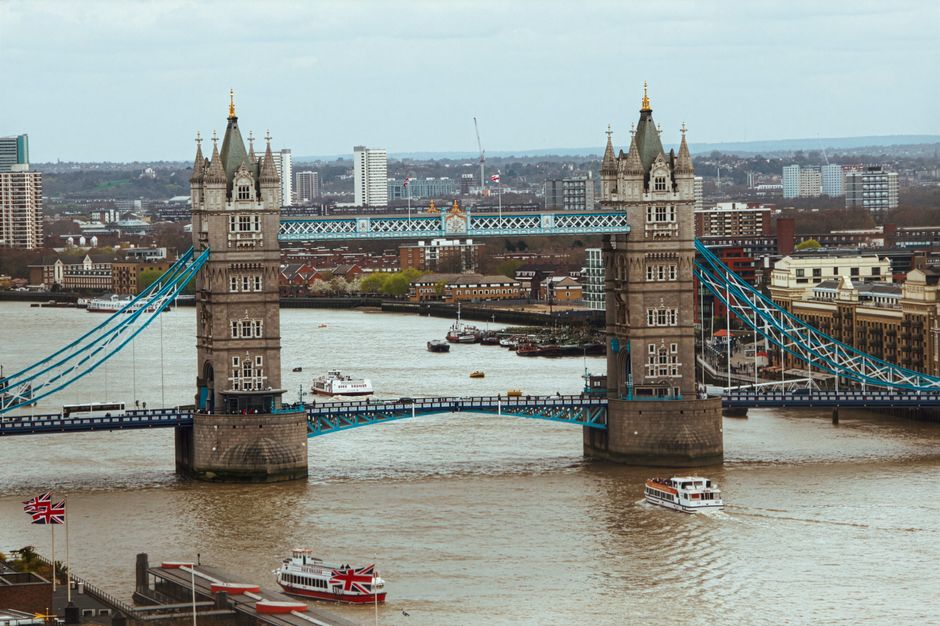 A view of Tower Bridge in Bermondsey, London, against a partly cloudy sky. The bridge's two large stone towers with decorative turrets are visible, connected by a central high-level walkway and suspen